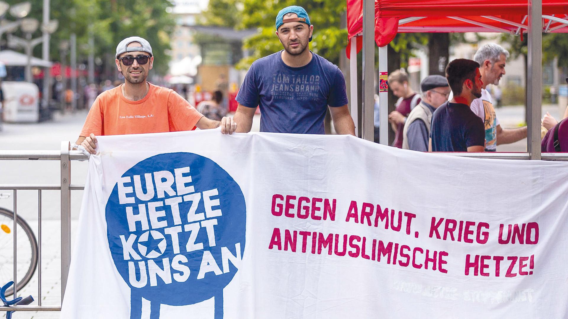 zwei Demonstranten mit einem Banner, auf dem antimuslimische Hetze verurteilt wird