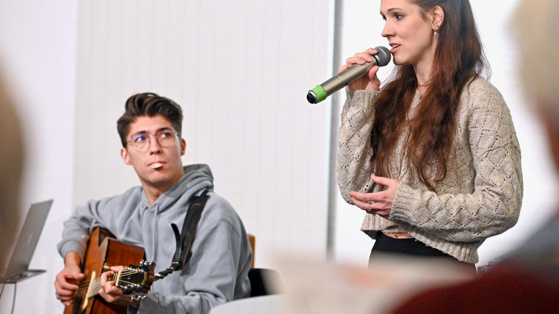 Eine Frau am Mikrofon, ein Mann spielt Gitarre.