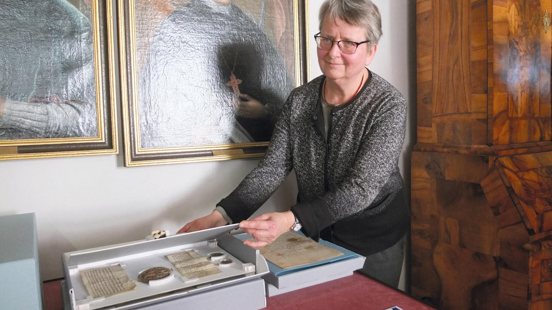 Birgit Mitzscherlich, Leiterin des Diözesanarchivs in Bautzen, steht an einem Tisch, auf dem eine alte Urkunde liegt