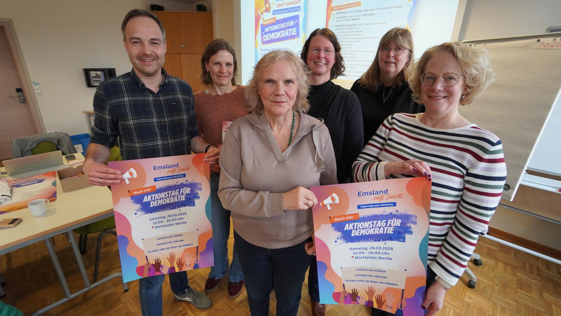 Sechs Frauen und Männer halten ein Plakat in die Kamera