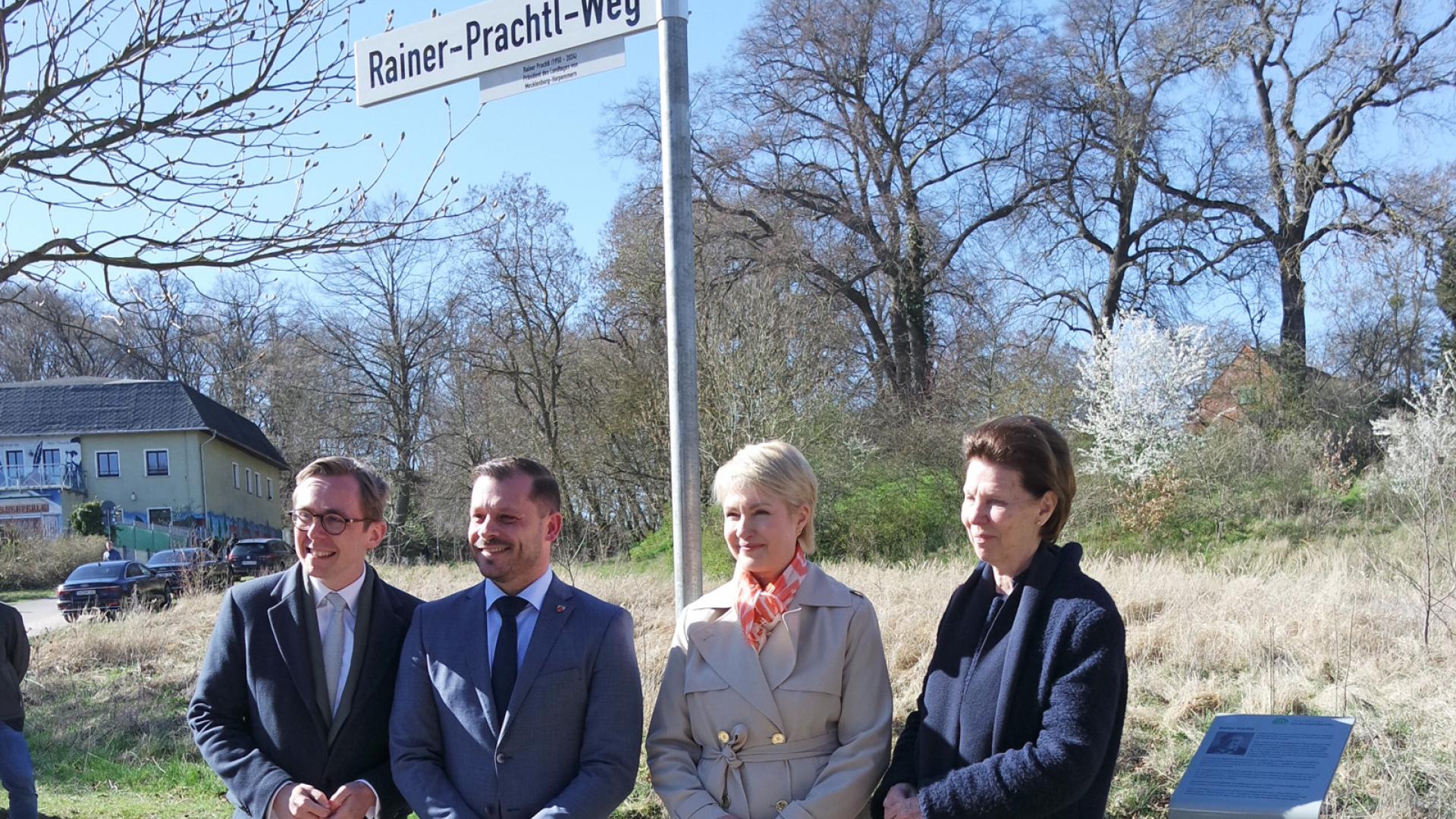 Menschen stehen vor einem Straßenschild mit dem Aufdruck Rainer-Prachtl-Weg.
