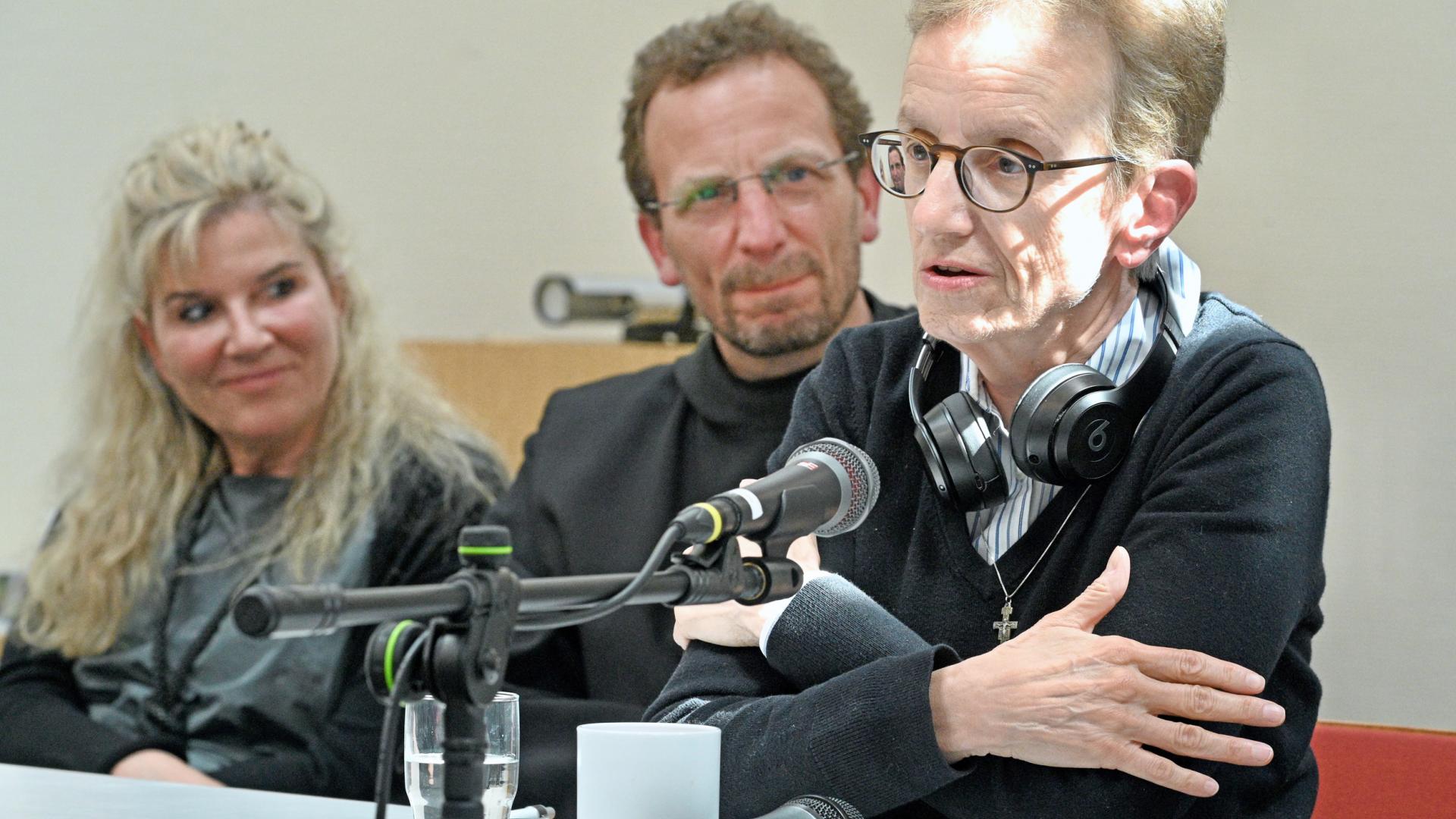Menschen sitzen an einem Tisch mit Mikrofon.