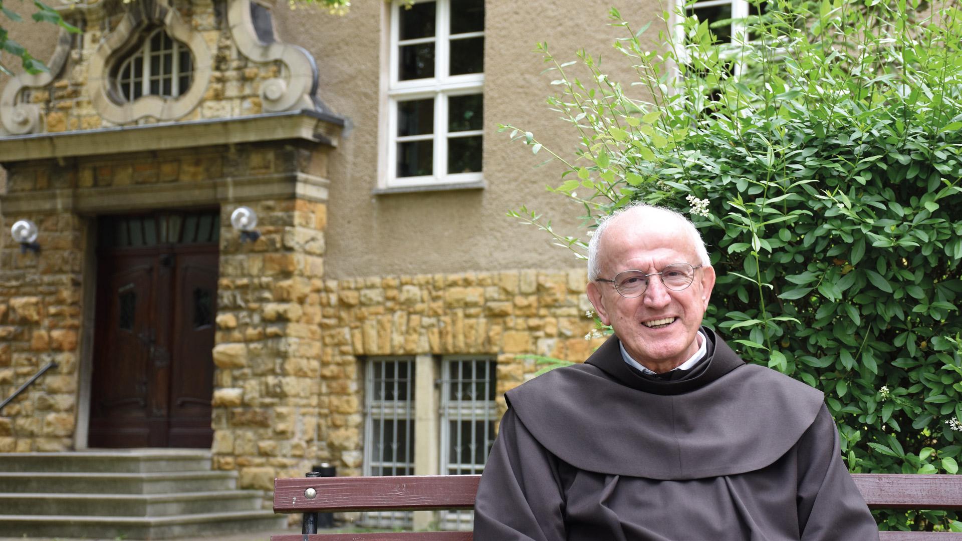 ein älterer Franziskanerpater sitzt vor dem Franziskanerkloster in Halle (Saale)