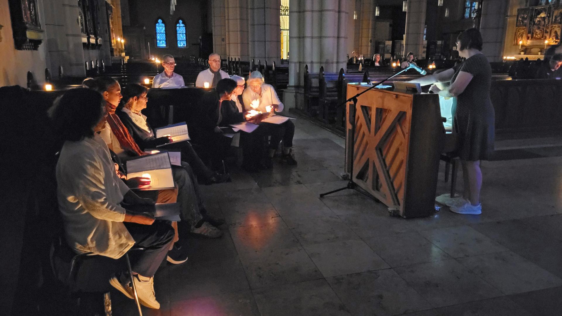 Menschen sitzen bei Kerzenschein in der Kirche.