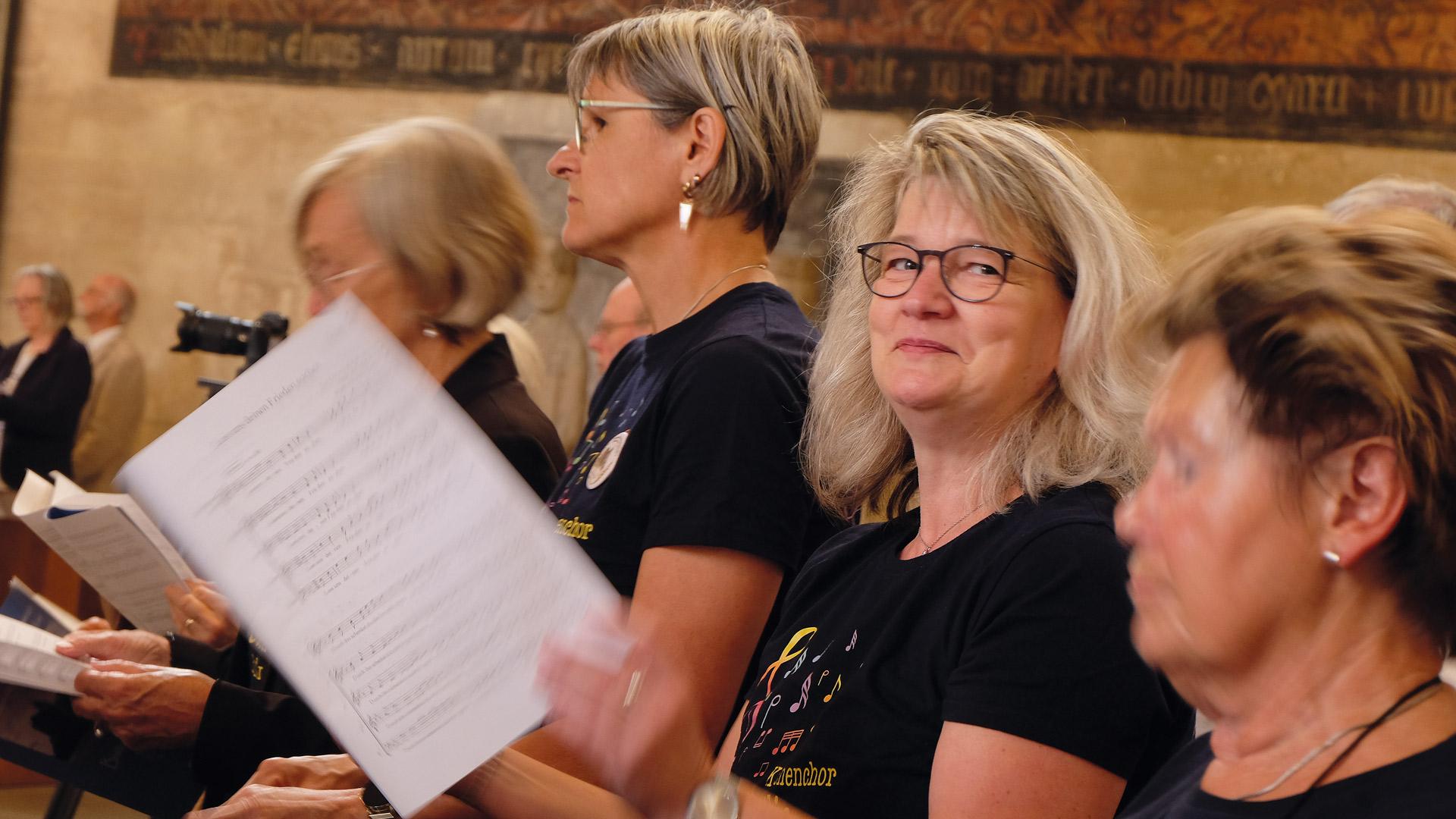 eine Chorsängerin guckt verschmitzt in die Kamera