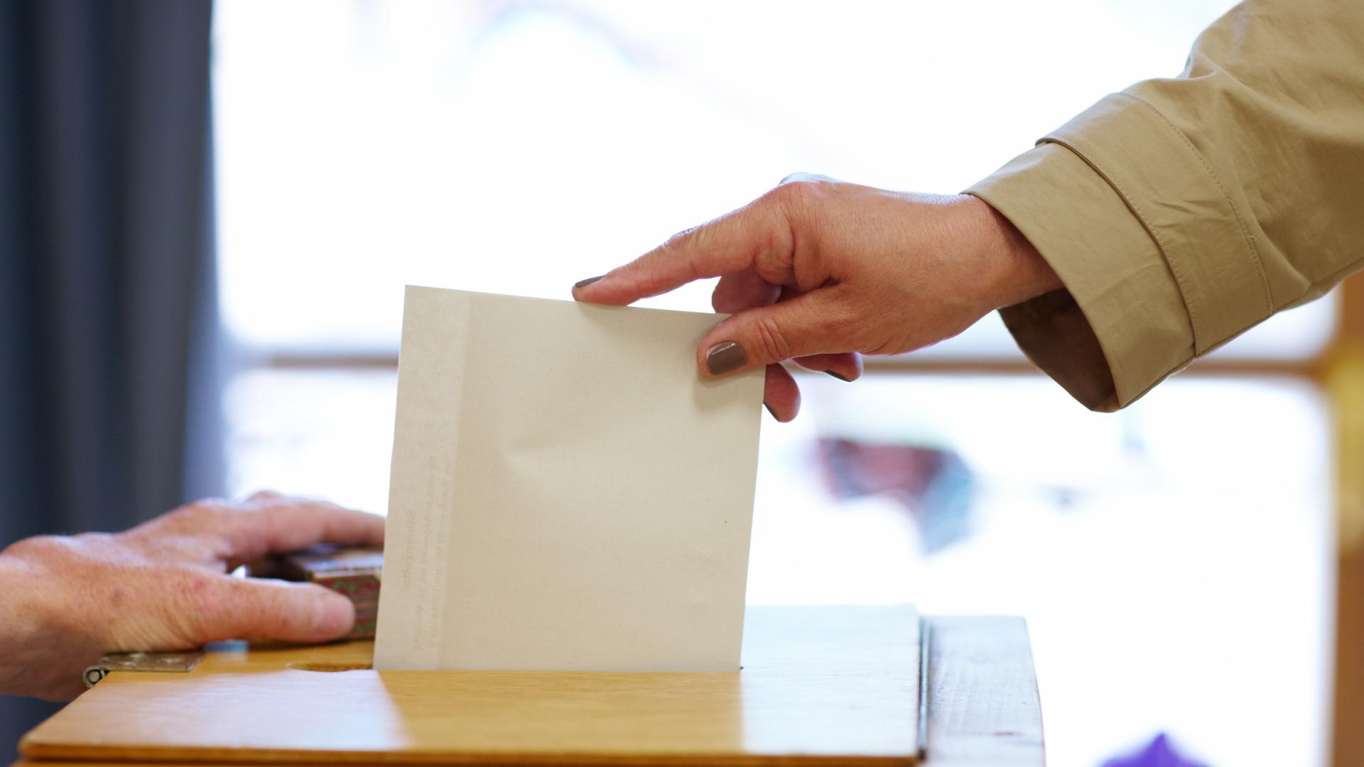 Ein Umschlag wird in eine Wahlurne gesteckt
