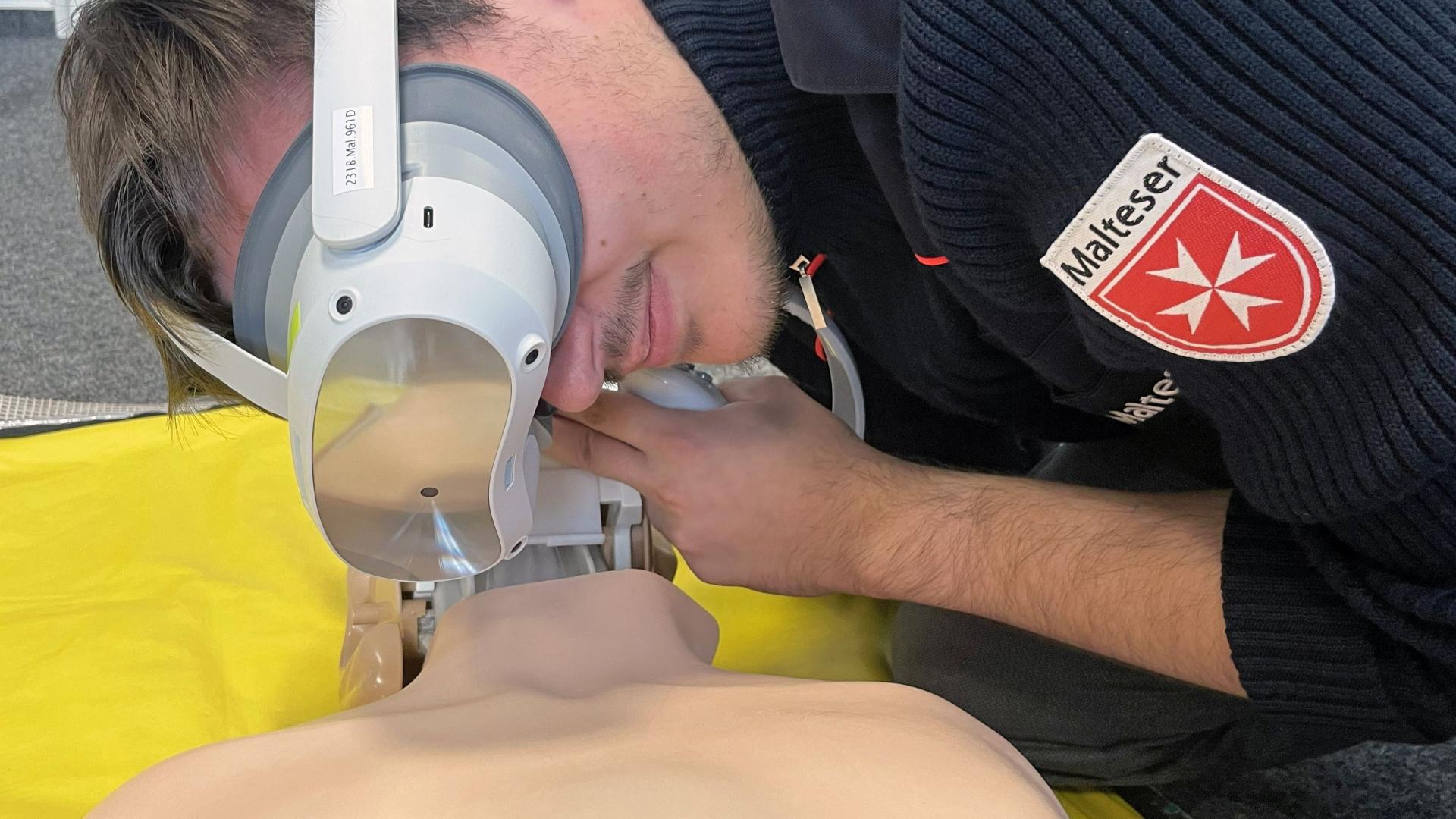 Ein Mann mit VR-Brille beugt sich über eine Simulationspuppe